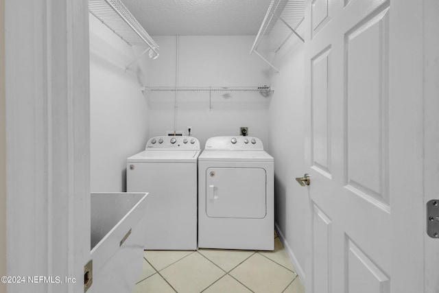 laundry area featuring a textured ceiling, separate washer and dryer, and light tile patterned floors