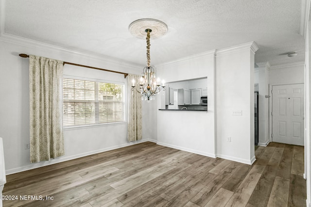 unfurnished dining area featuring crown molding, a notable chandelier, wood-type flooring, and a textured ceiling