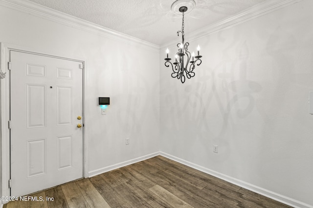 unfurnished dining area with ornamental molding, a textured ceiling, a notable chandelier, and wood-type flooring