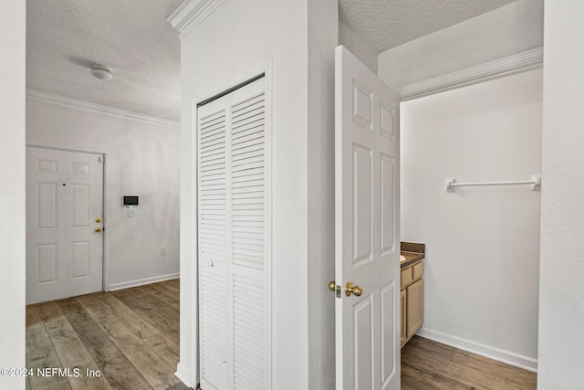 corridor with crown molding, a textured ceiling, and dark hardwood / wood-style floors