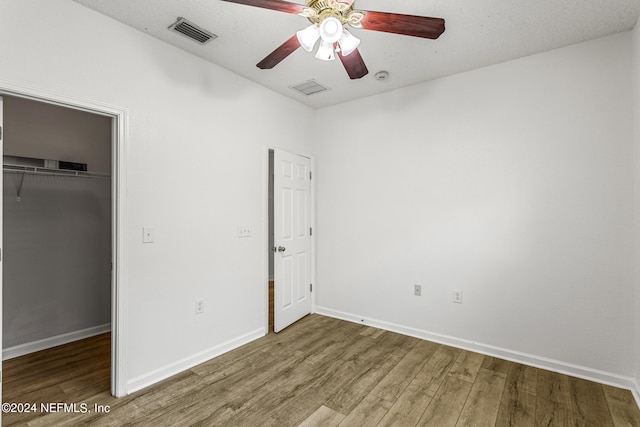 unfurnished bedroom featuring a textured ceiling, hardwood / wood-style flooring, a closet, and ceiling fan