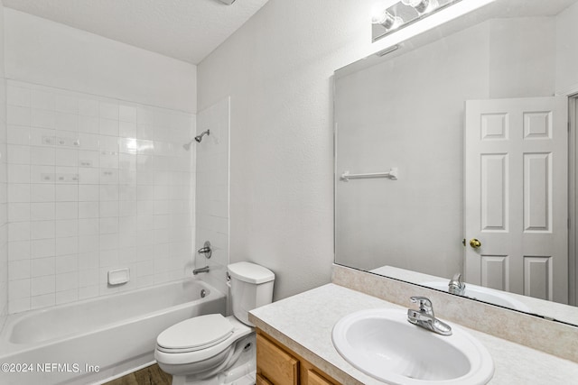 full bathroom with a textured ceiling, hardwood / wood-style flooring, toilet, vanity, and tiled shower / bath combo