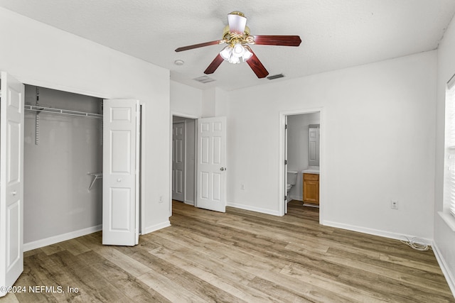 unfurnished bedroom with ensuite bath, a textured ceiling, a closet, ceiling fan, and light hardwood / wood-style flooring