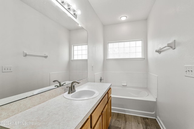 bathroom with vanity, a textured ceiling, hardwood / wood-style flooring, and a tub