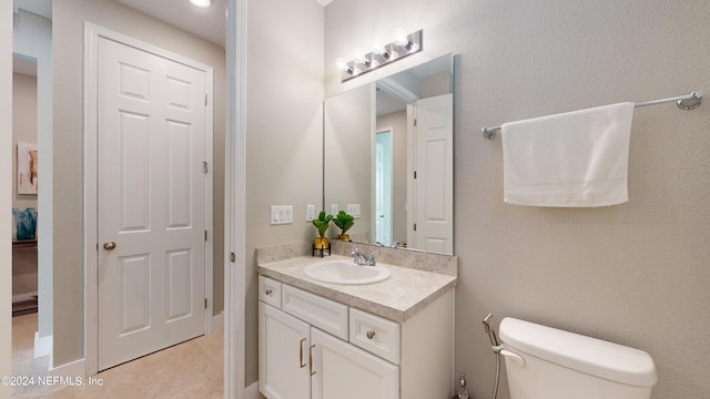 bathroom with toilet, vanity, and tile patterned flooring