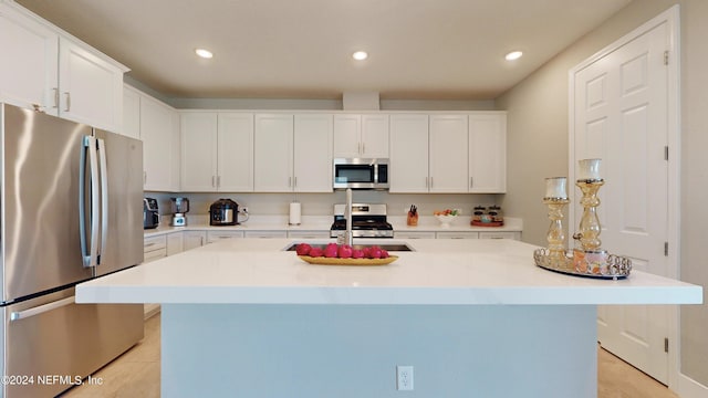 kitchen featuring appliances with stainless steel finishes, a kitchen island with sink, white cabinetry, and light tile patterned flooring