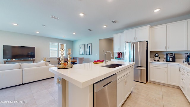 kitchen with appliances with stainless steel finishes, white cabinetry, sink, and an island with sink