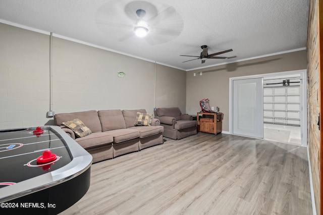 living room with ceiling fan, a textured ceiling, ornamental molding, and light wood-type flooring