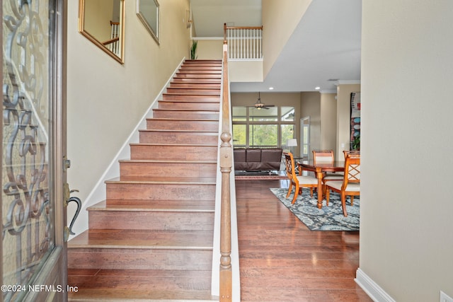 stairway with crown molding, wood-type flooring, and ceiling fan