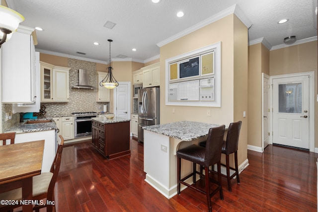 kitchen featuring appliances with stainless steel finishes, a kitchen island, decorative light fixtures, dark wood-type flooring, and light stone counters