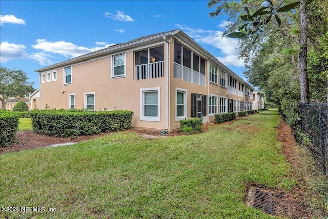 view of side of home with a sunroom and a lawn