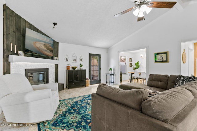 living room featuring a large fireplace, a textured ceiling, ceiling fan, high vaulted ceiling, and light tile patterned floors