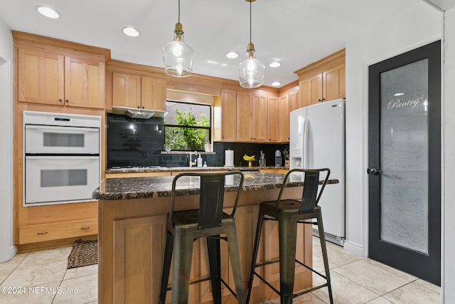 kitchen with white appliances, a kitchen island, pendant lighting, decorative backsplash, and light brown cabinets