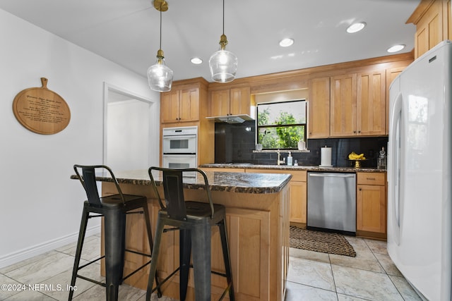 kitchen with decorative backsplash, hanging light fixtures, dark stone counters, a center island, and white appliances