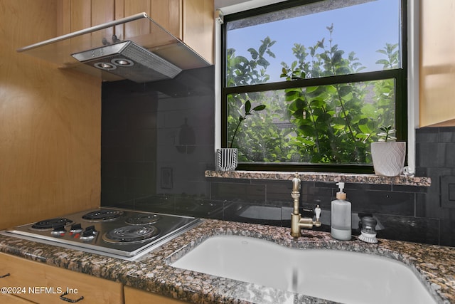 kitchen with decorative backsplash, sink, white cooktop, and dark stone counters