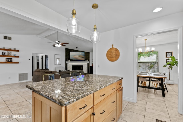 kitchen with vaulted ceiling with beams, a large fireplace, a center island, dark stone countertops, and light brown cabinets