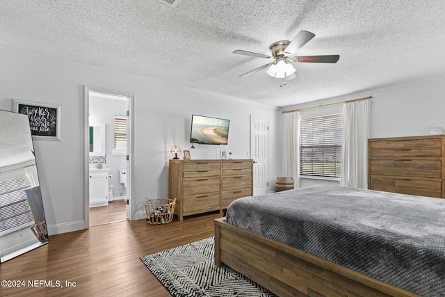 bedroom featuring a textured ceiling, ceiling fan, dark hardwood / wood-style floors, and ensuite bath