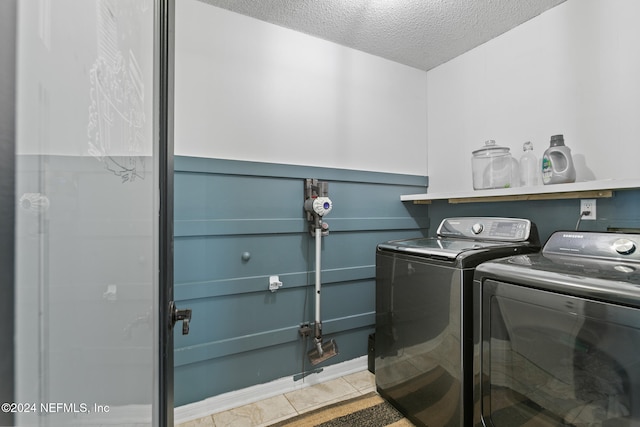 clothes washing area featuring tile patterned floors, a textured ceiling, and washing machine and clothes dryer