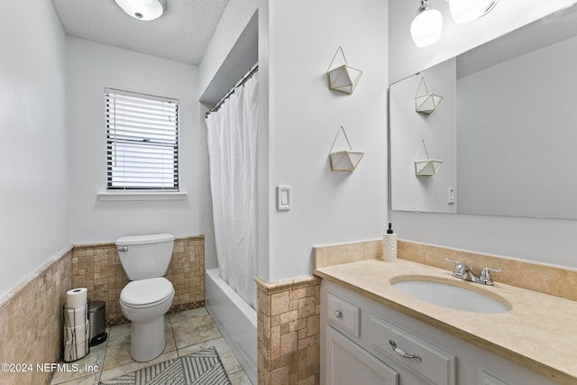 full bathroom with vanity, tile walls, shower / bath combination with curtain, and toilet