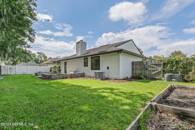 back of property with central air condition unit and a lawn