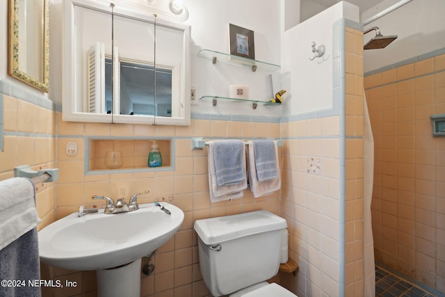 bathroom featuring toilet, curtained shower, sink, and tile walls