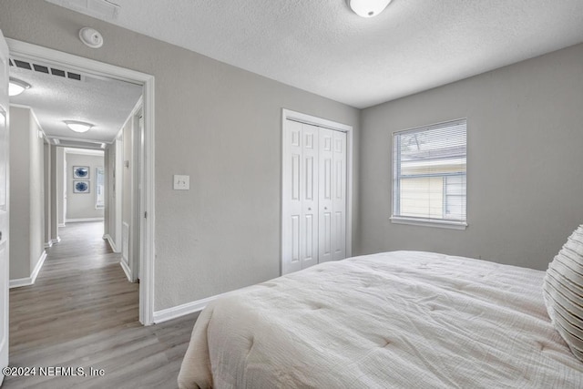 bedroom with light hardwood / wood-style floors, a closet, and a textured ceiling