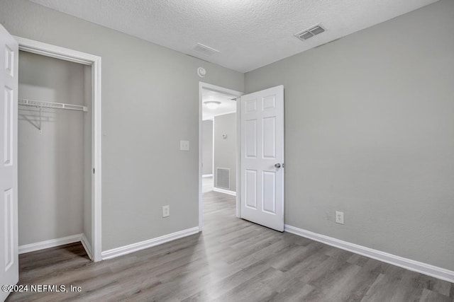 unfurnished bedroom with a closet, wood-type flooring, and a textured ceiling