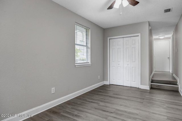 unfurnished bedroom featuring a closet, hardwood / wood-style flooring, and ceiling fan