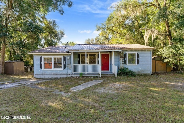 ranch-style home with a shed, a front yard, and a porch