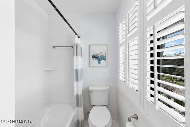 bathroom featuring shower / tub combo with curtain, tile walls, and toilet