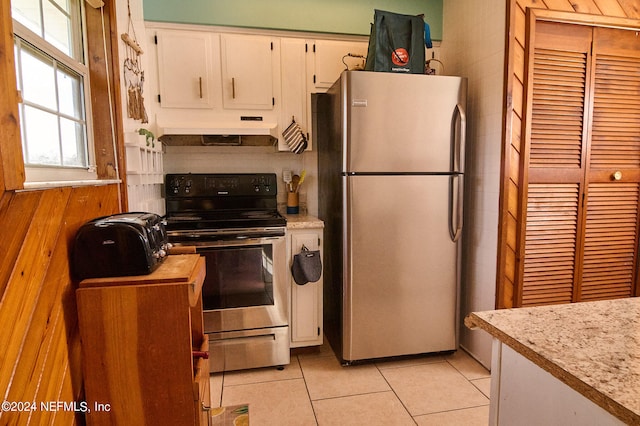 kitchen featuring wood walls, white cabinetry, light tile patterned flooring, and stainless steel appliances