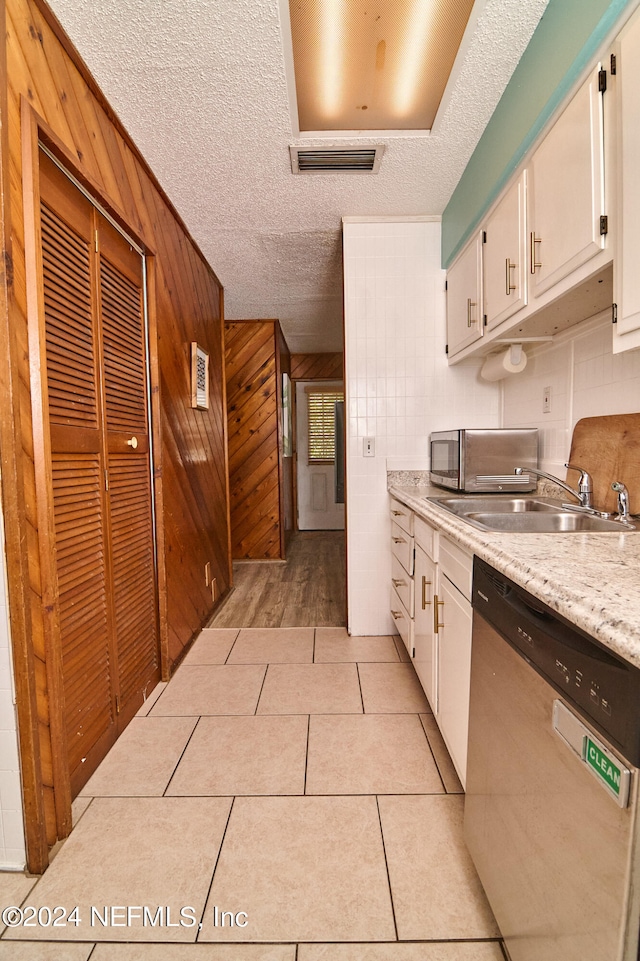 kitchen with light tile patterned flooring, white cabinetry, appliances with stainless steel finishes, a textured ceiling, and wooden walls