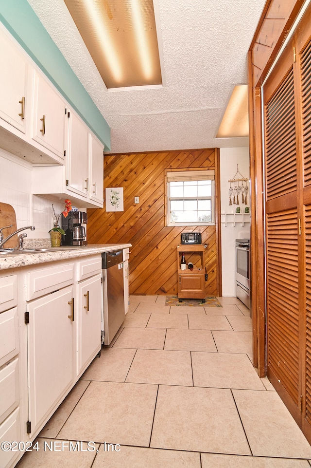 kitchen with light tile patterned floors, white cabinetry, and wooden walls