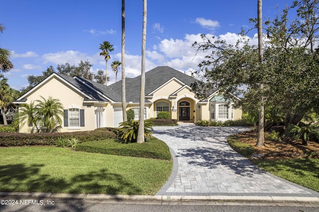 view of front of property with a front yard, stucco siding, and decorative driveway
