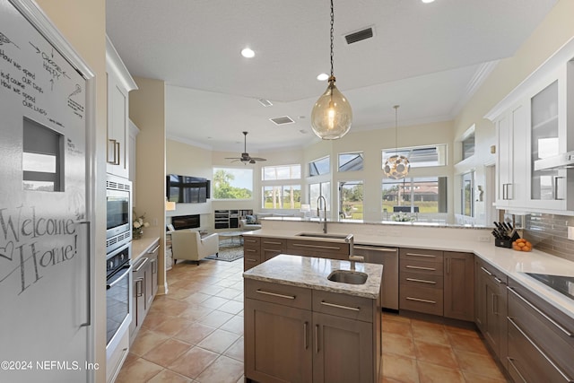 kitchen with ornamental molding, open floor plan, a sink, and visible vents