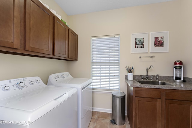 laundry area featuring washer and clothes dryer, a sink, light tile patterned floors, cabinet space, and baseboards