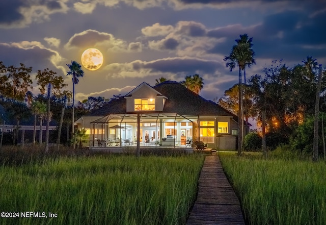 back house at dusk featuring glass enclosure