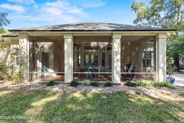 back of house featuring a sunroom, ceiling fan, and a lawn