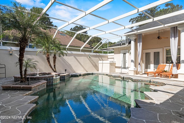 view of pool with french doors, ceiling fan, a lanai, a patio area, and a hot tub