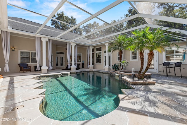 view of swimming pool featuring an in ground hot tub, french doors, a lanai, and a patio area