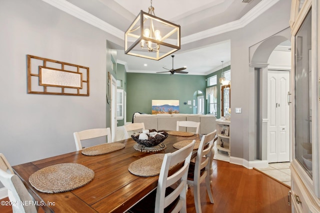 dining area featuring ceiling fan with notable chandelier, light wood-type flooring, crown molding, and decorative columns