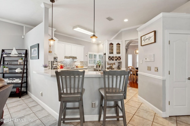 kitchen featuring kitchen peninsula, a kitchen breakfast bar, crown molding, white cabinetry, and hanging light fixtures