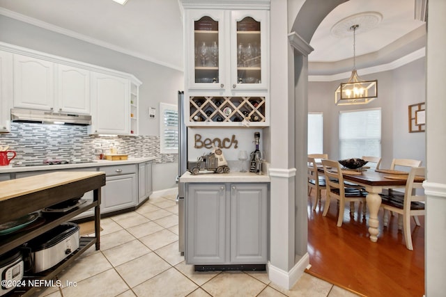 kitchen featuring light tile patterned flooring, crown molding, white cabinets, and hanging light fixtures