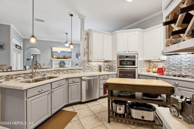 kitchen with hanging light fixtures, crown molding, sink, appliances with stainless steel finishes, and white cabinetry