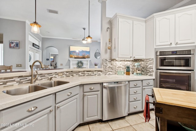 kitchen with white cabinetry, sink, stainless steel appliances, decorative light fixtures, and ornamental molding