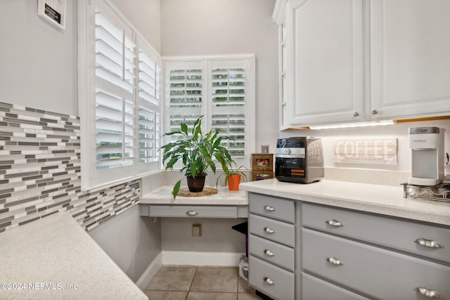 kitchen featuring decorative backsplash, gray cabinetry, built in desk, white cabinetry, and light tile patterned flooring