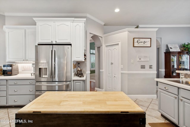 kitchen with stainless steel fridge, ornamental molding, light tile patterned floors, white cabinets, and gray cabinets