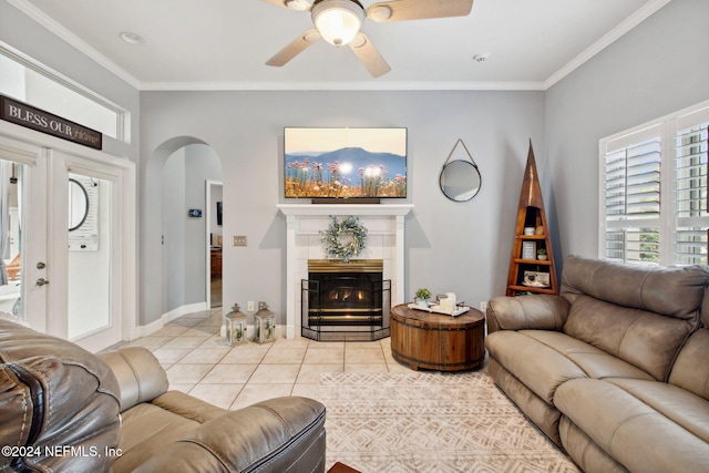 living room featuring a tile fireplace, light tile patterned floors, ceiling fan, and ornamental molding