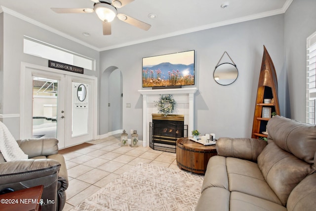 tiled living room featuring a tile fireplace, french doors, ceiling fan, and crown molding