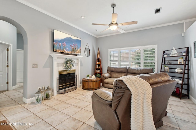 living room featuring ceiling fan, a fireplace, light tile patterned flooring, and ornamental molding